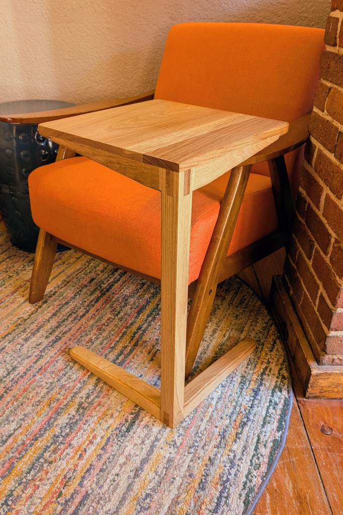 Cantilevered side table by orange lounge chair